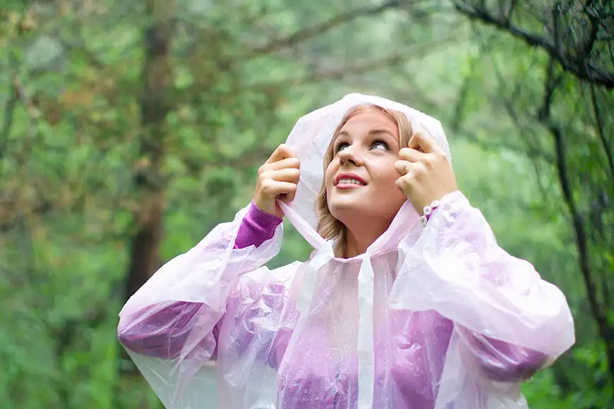  woman in plastic rain poncho forest looking up