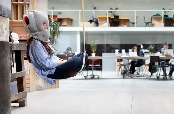 Woman sitting on a hammock using the Ostrich Pillow