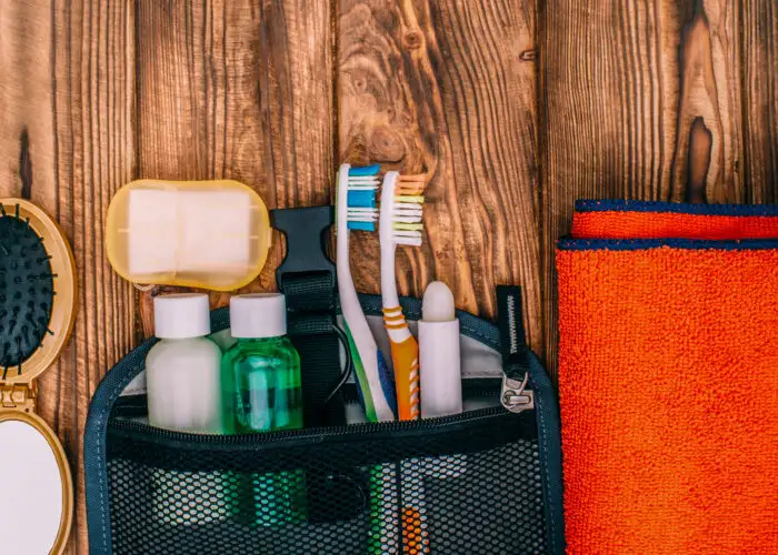 top view of a toiletry kit with toothbrush shampoo soap and towel