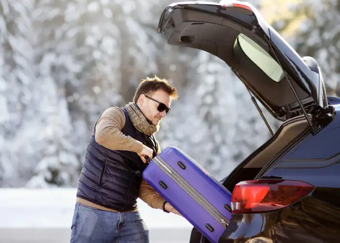 man packing luggage in car road trip