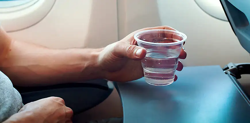 passenger holds glass of water on plane
