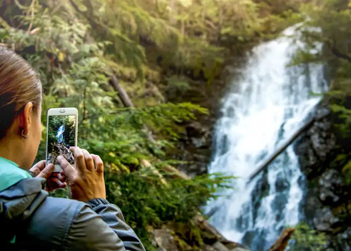 person taking photo or video of waterfall smartphone iphone