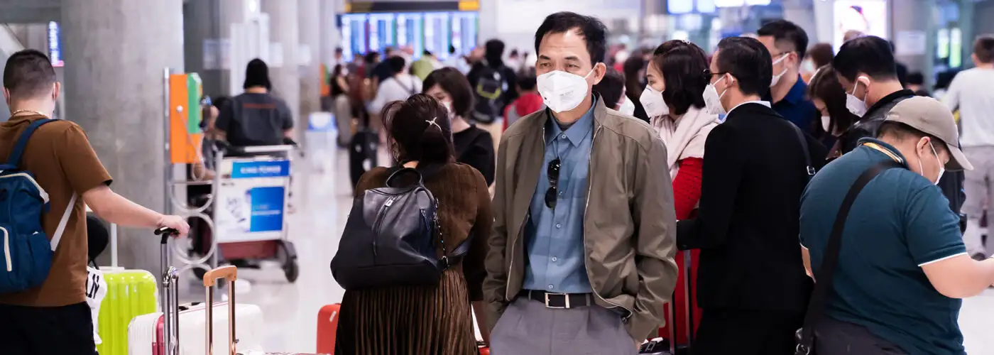 man in mask at crowded airport.