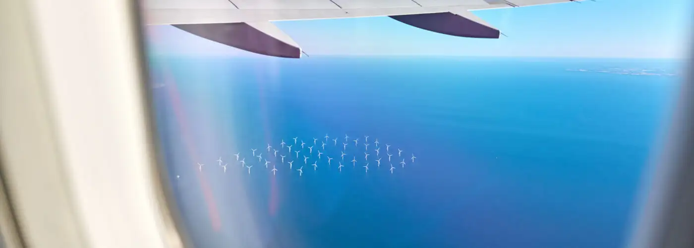 airplane flying over an ocean wind farm