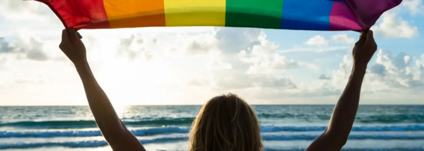 rainbow flag held by a woman's silhouette