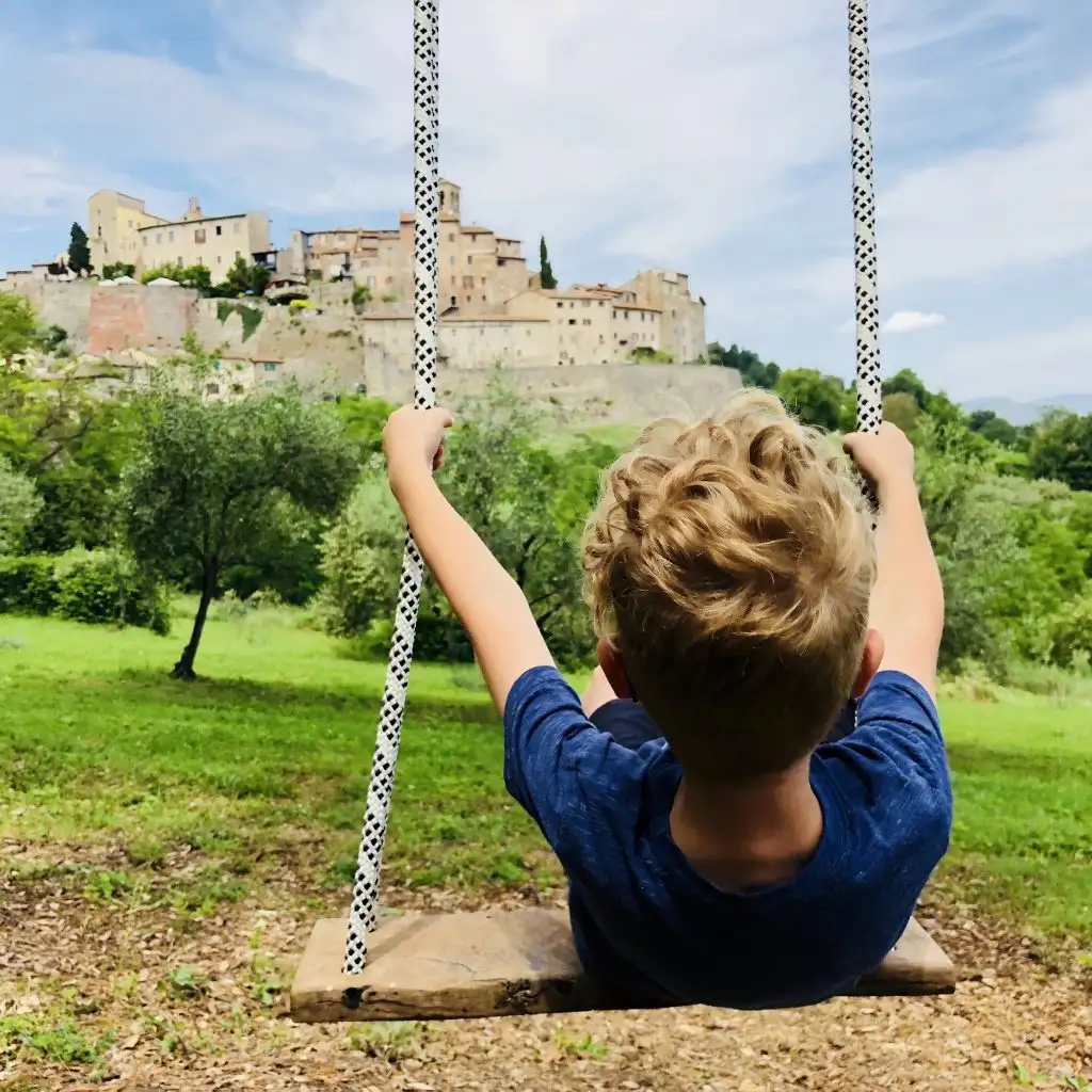 Child swinging with a view of tuscan hill town
