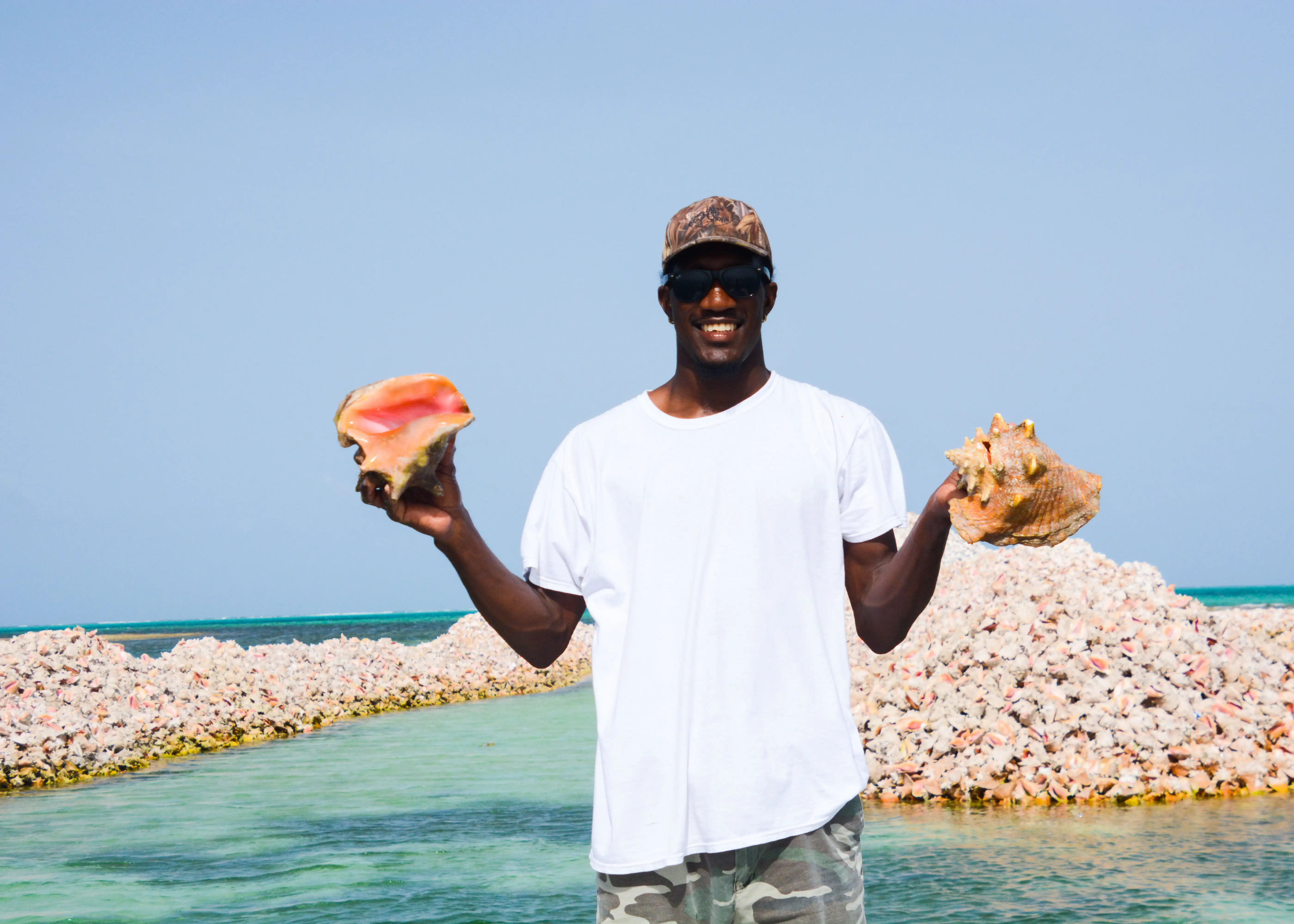 Man holding conch shells on anegada in the bvi