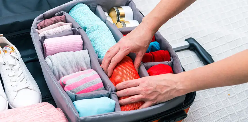 man rolling clothes into a suitcase