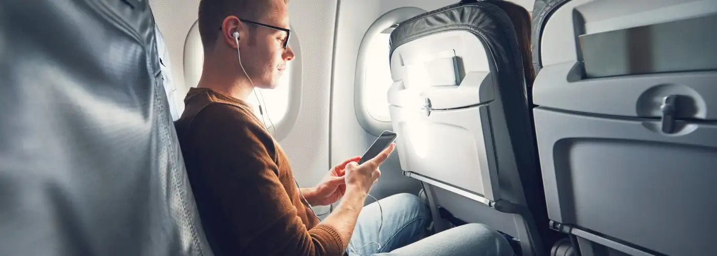 Man on airplane wearing headphones - hero