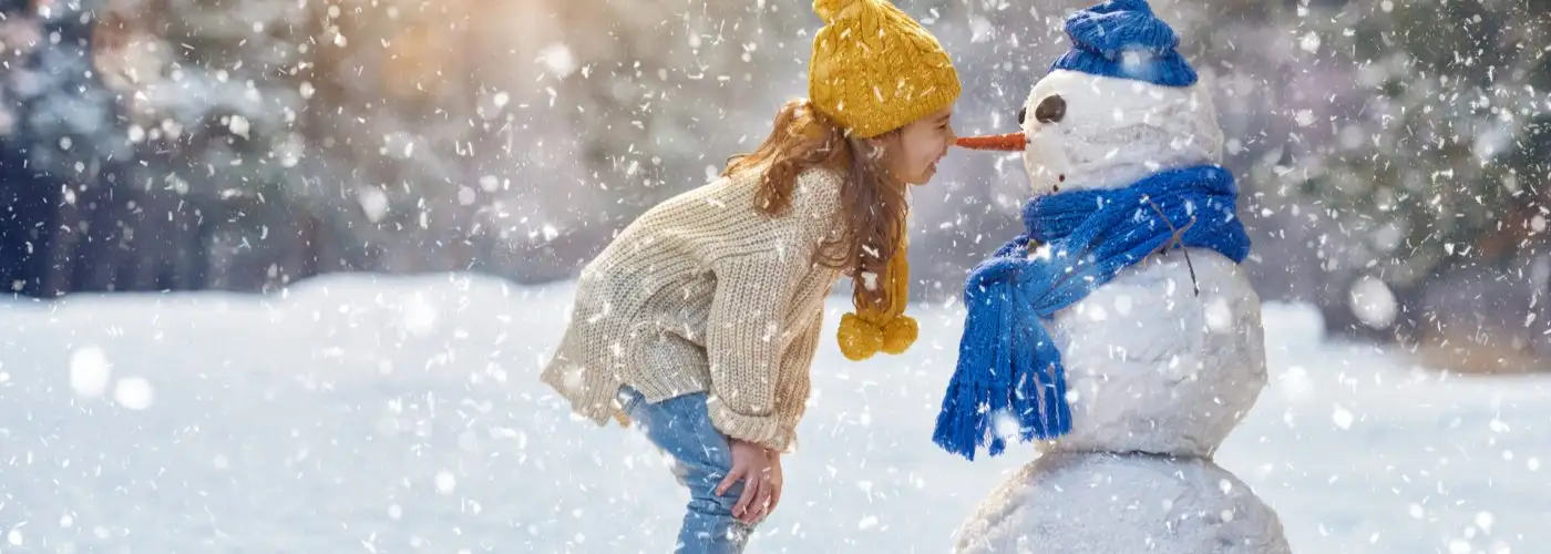 girl playing with snowman on a snowy winter walk