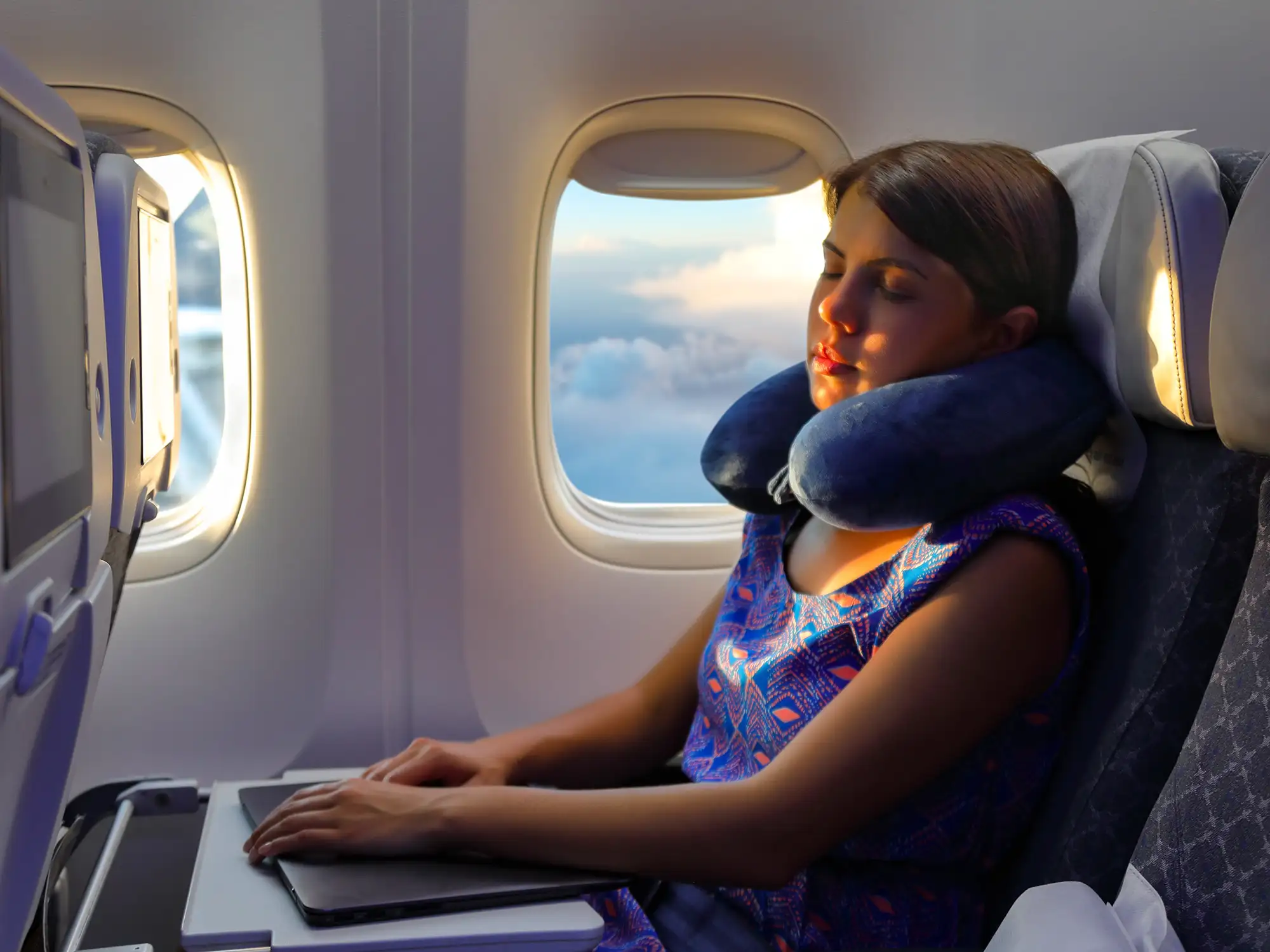 https://www.smartertravel.com/wp-content/webp-express/webp-images/doc-root/wp-content/uploads/2018/11/neck-pillow-flight-woman-sleep.jpg.webp