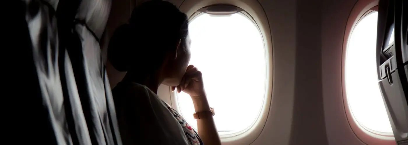 woman looking out airplane window.