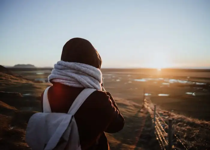 traveler with scarf and backpack at sunset