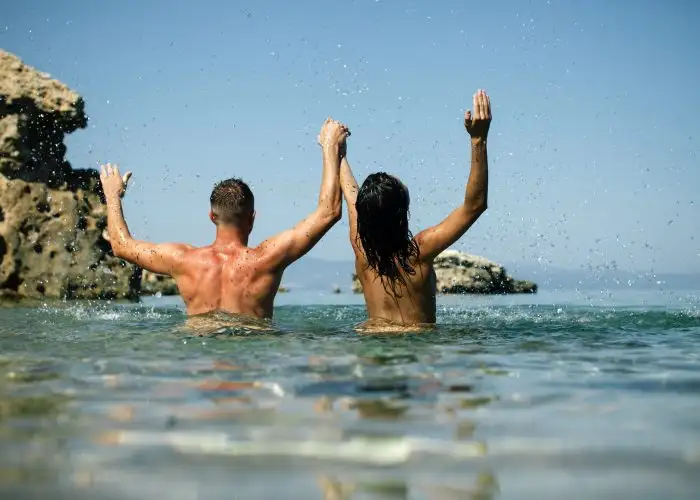 couple splashing water nude beach