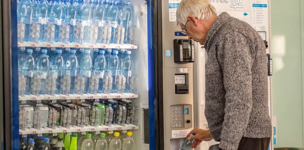 man purchasing bottled water from vending machine airport