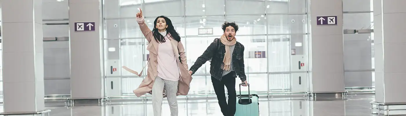 Young couple running through empty airport to catch flight