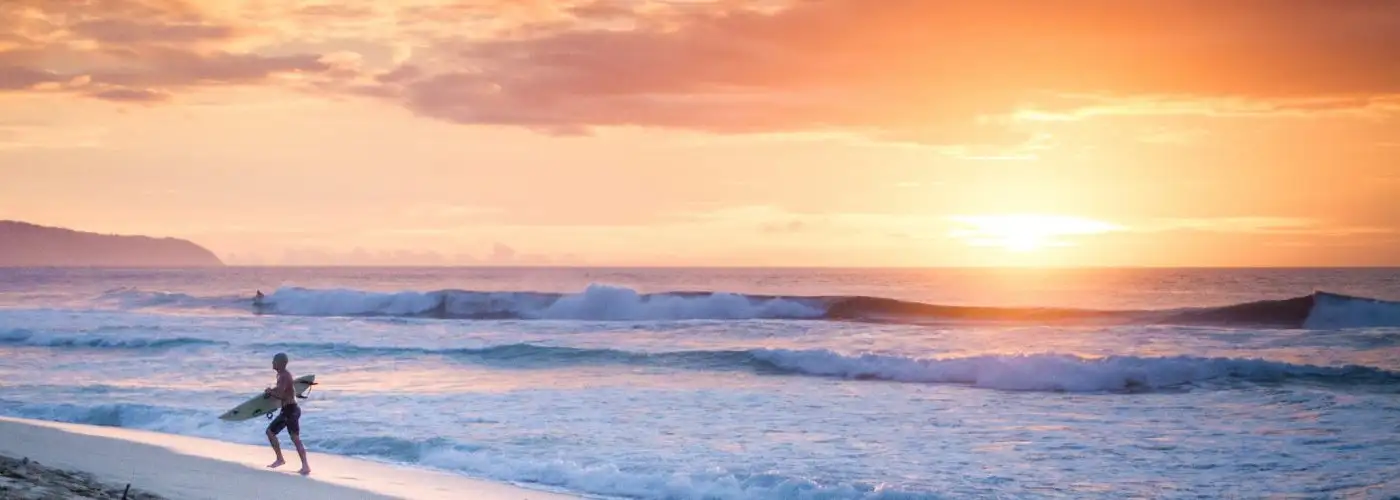 surfer on beach at sunset in Hawaii