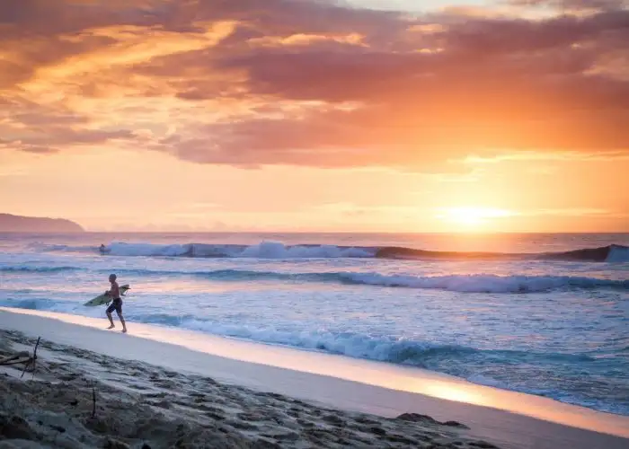 surfer on beach at sunset in Hawaii