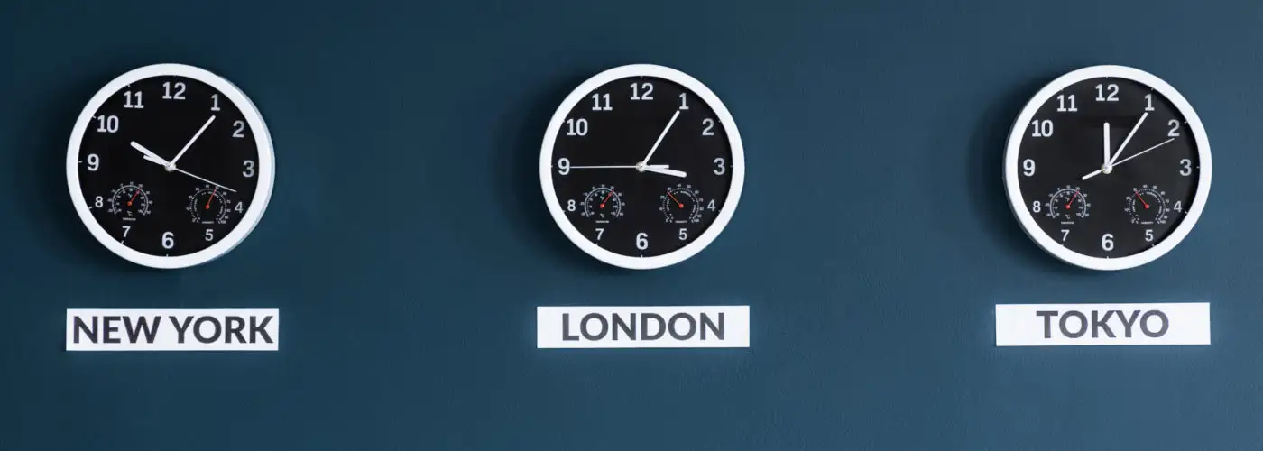 Three clocks on a dark blue wall showing the times in New York, London, and Tokyo