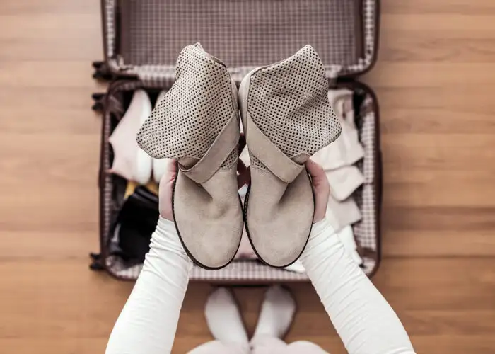 op view of woman hands packing a boots in a luggage