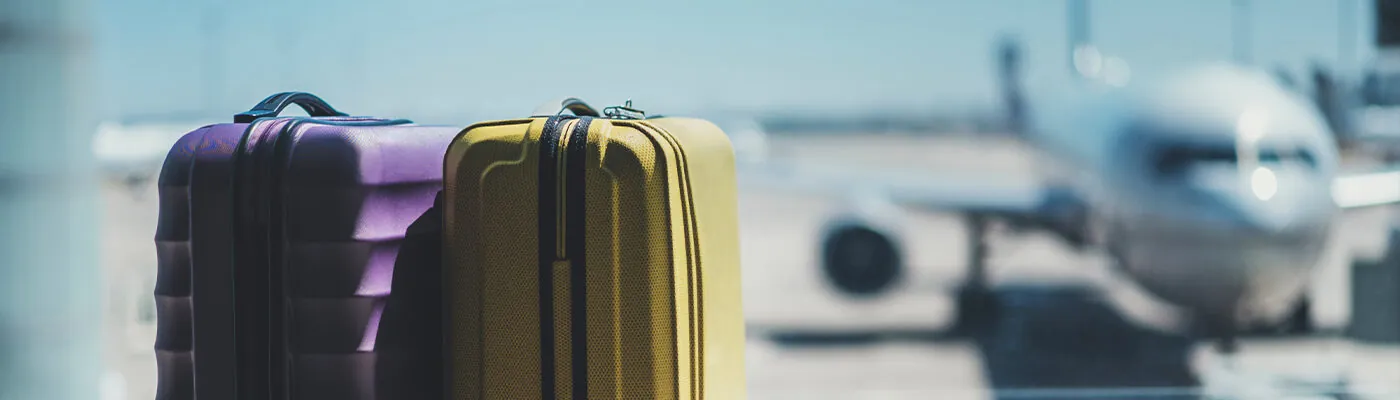 Suitcases sitting in front of large window at airport, through which an out-of-focus airplane can be seen