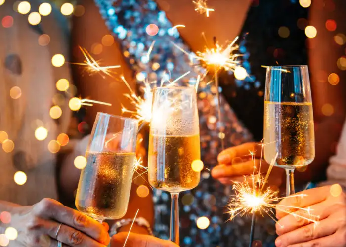 Close up of a champagne toast and people holding sparklers on New Year's Eve