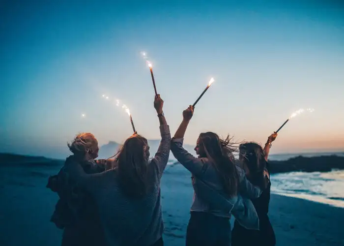 friends celebrating new years eve with sparklers on beach