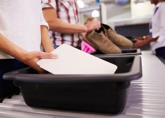 People placing items in bins at airport security