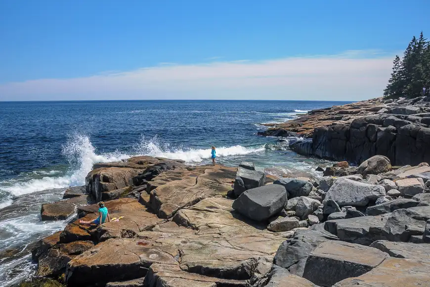 Children watching waves to hit the rocky coast of Maine at Schoodic Point 