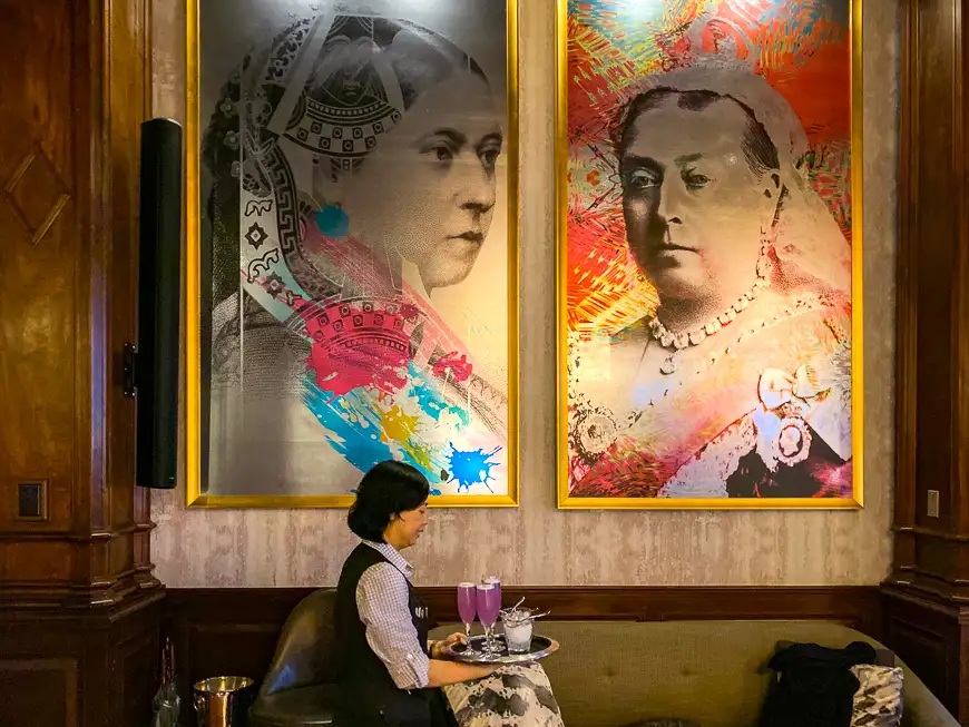server walks past two portraits of Queen Victoria in British Columbia, Canada