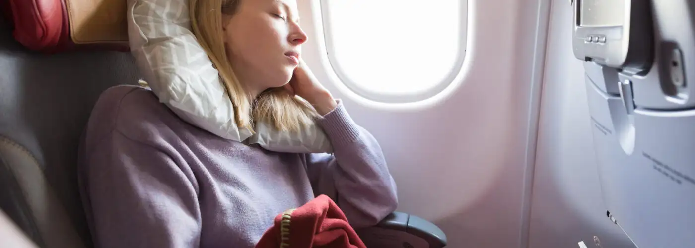 woman sleeping on plane in window seat