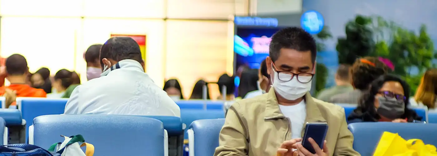 man wearing mask to protect against covid-19 coronavirus sits in airport gate