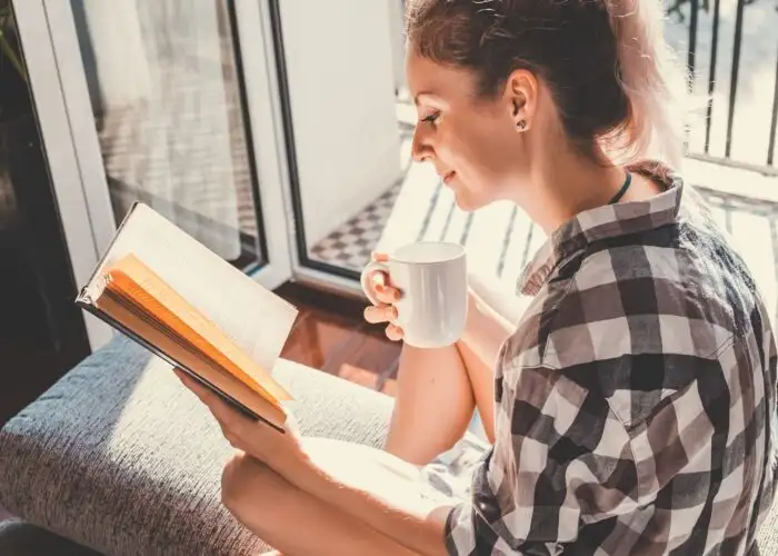 woman reading book with cup of coffee.