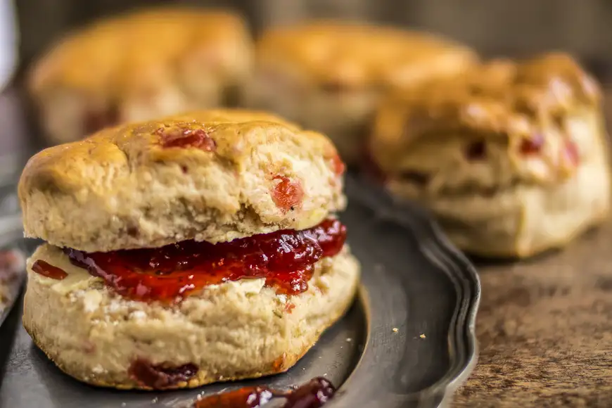 Cherry Scone with strawberry jam. in close up. Out of focus scones in the background.