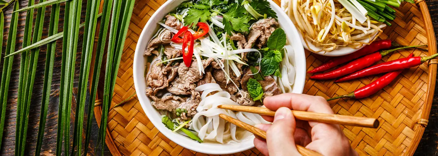 Pho Bo vietnamese Soup with beef and chopsticks in male hand