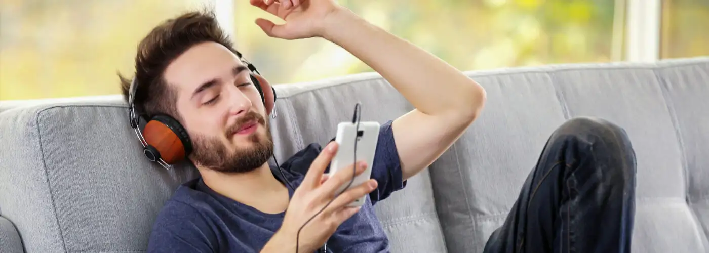 man listening to heapdphones on grey sofa