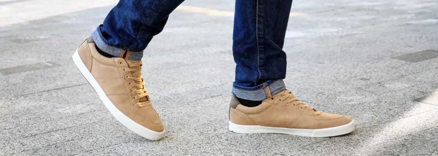 Close-up of man wearing tan sneakers and crossing the street
