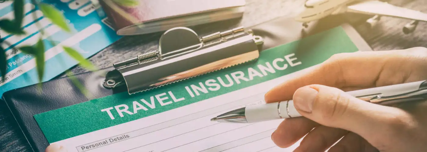 Person filling out travel insurance forms on decorated table