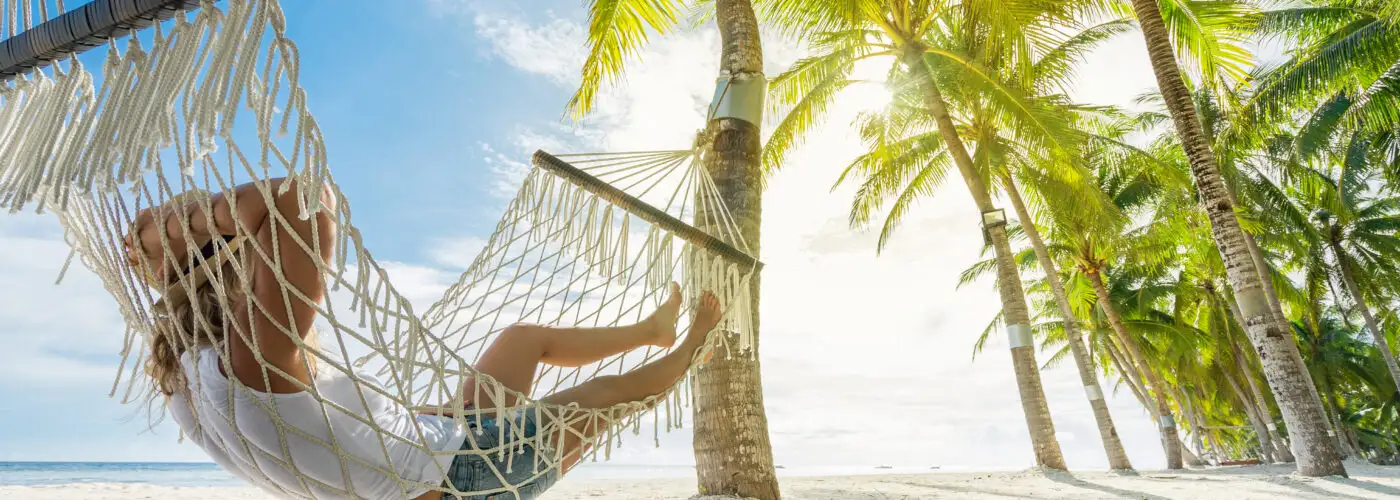 Person relaxing in hammock on beach