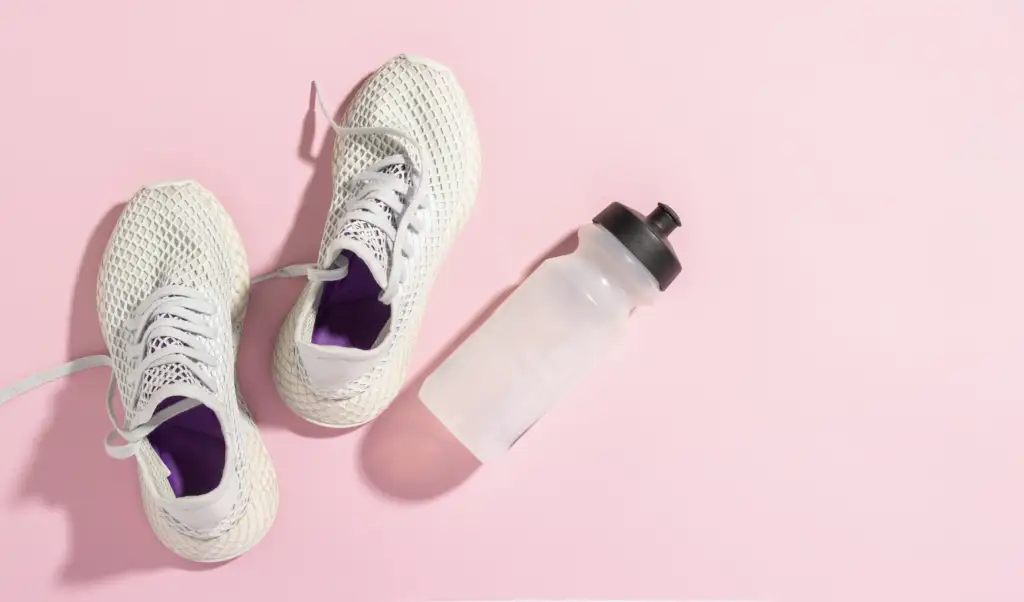 Sneakers and a water bottle on a pink background