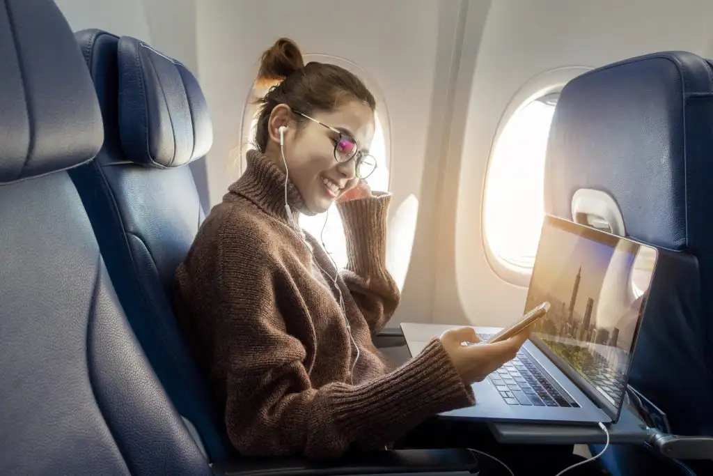 Woman using laptop and phone on flight