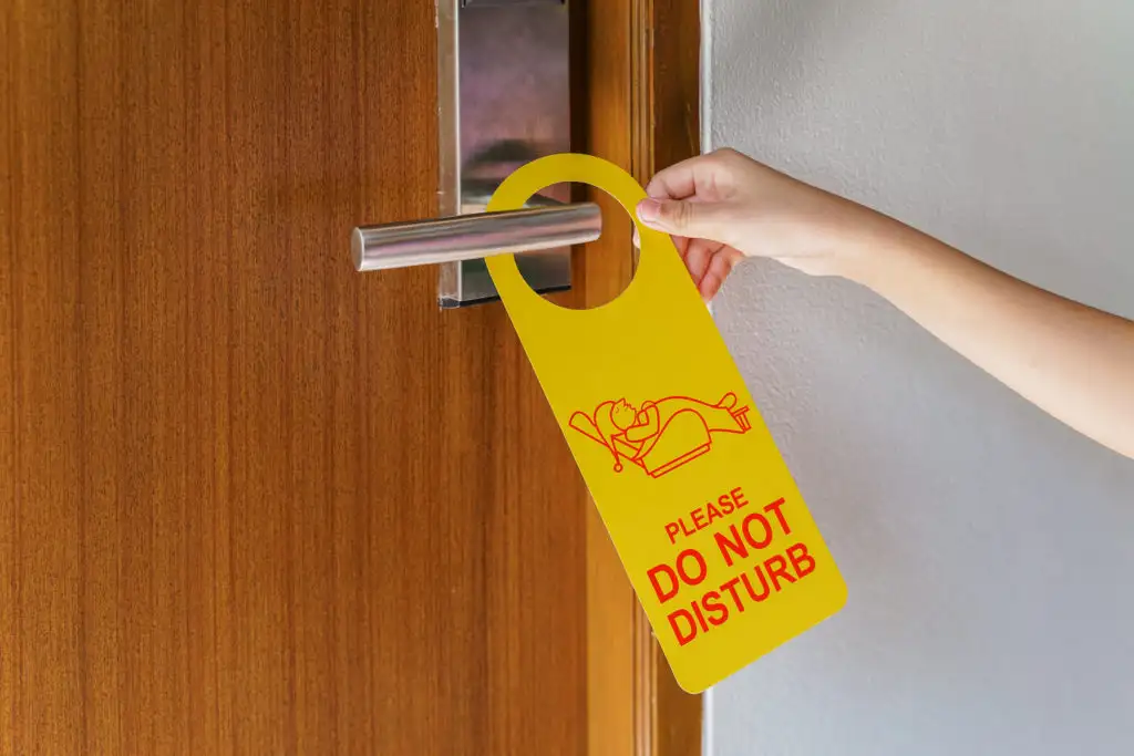 Person hanging a Do Not Disturb sign on hotel room door