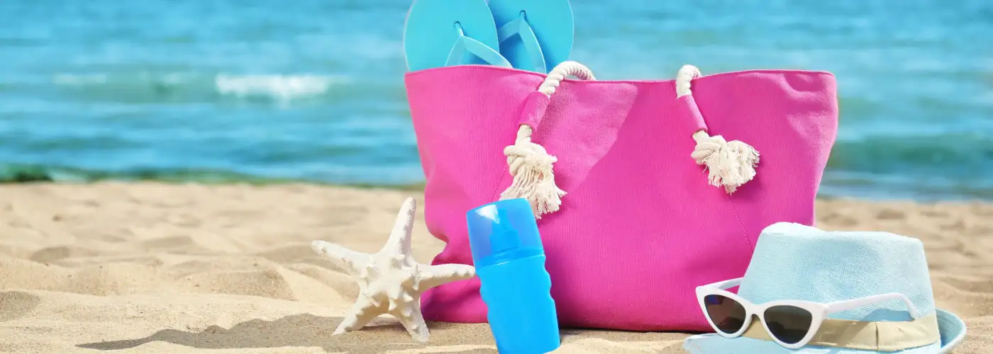 Pink beach bag with blue accessories on the beach