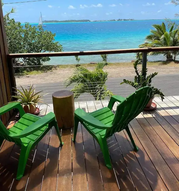 Two green chairs on a deck facing out toward a beach and ocean view in Bora Bora, French Polynesia