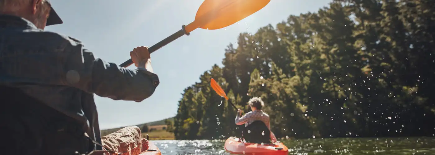 Two people kayaking on a lake on a sunny day