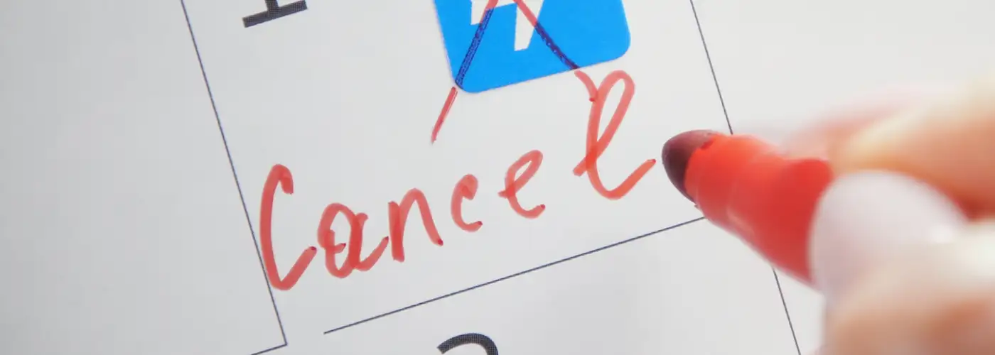 Person crossing out a flight emoji in red pen and writing "cancel" below it on a calendar