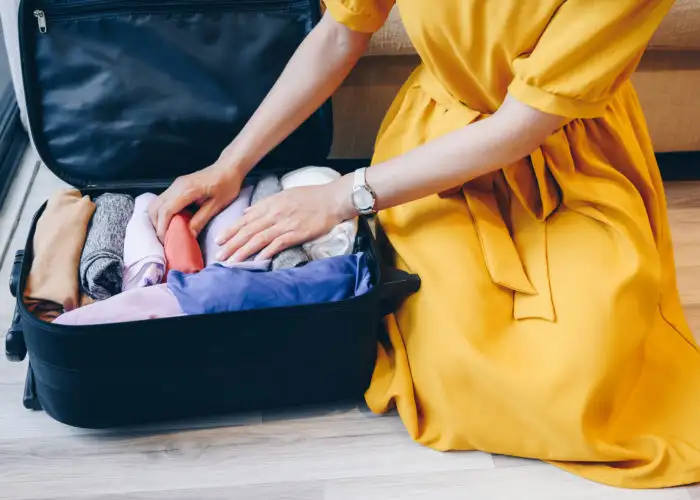 Close up of person in yellow dress packing a suitcase