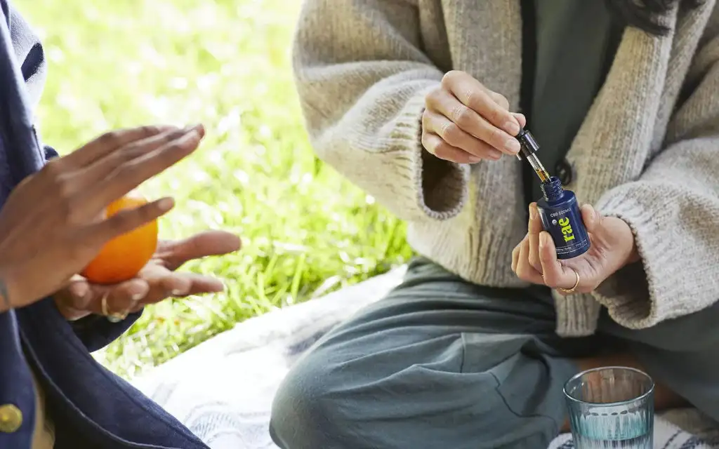 Two people sharing drops from a bottle of Rae CBD Drops 