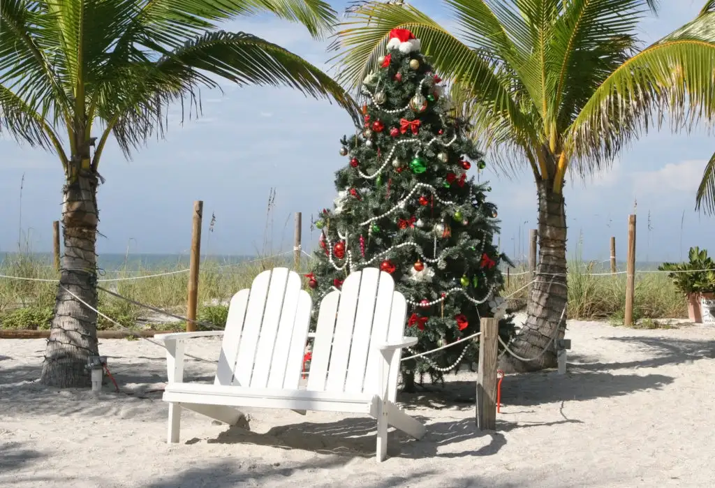 Christmas tree behind two lounge chairs on the beach