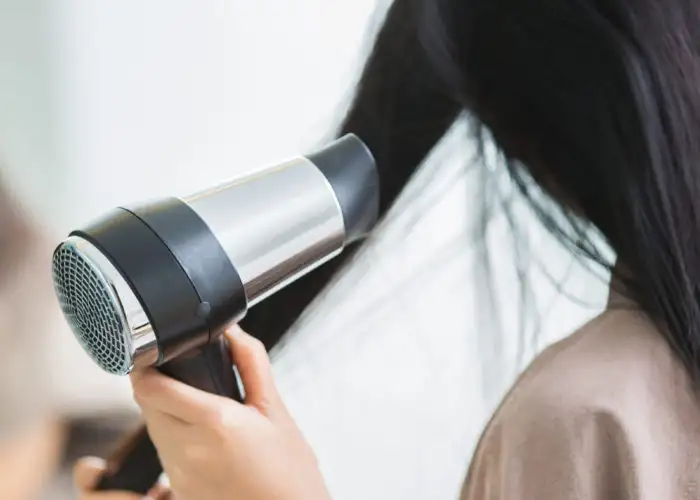 Close up of woman drying her hair with hair dyer